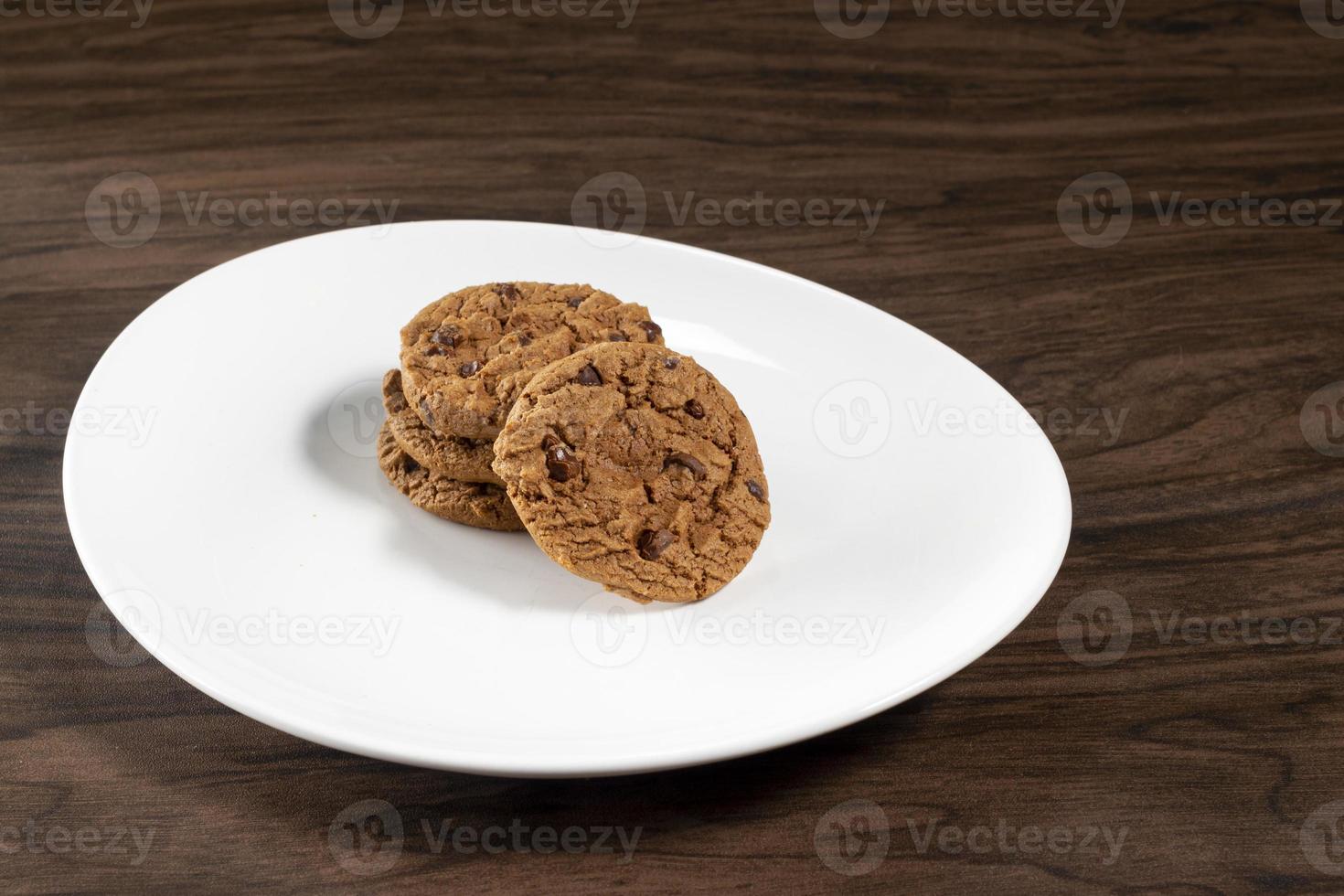 plato de galletas con trocitos de chocolate recién horneadas. fondo de madera, enfoque selectivo foto