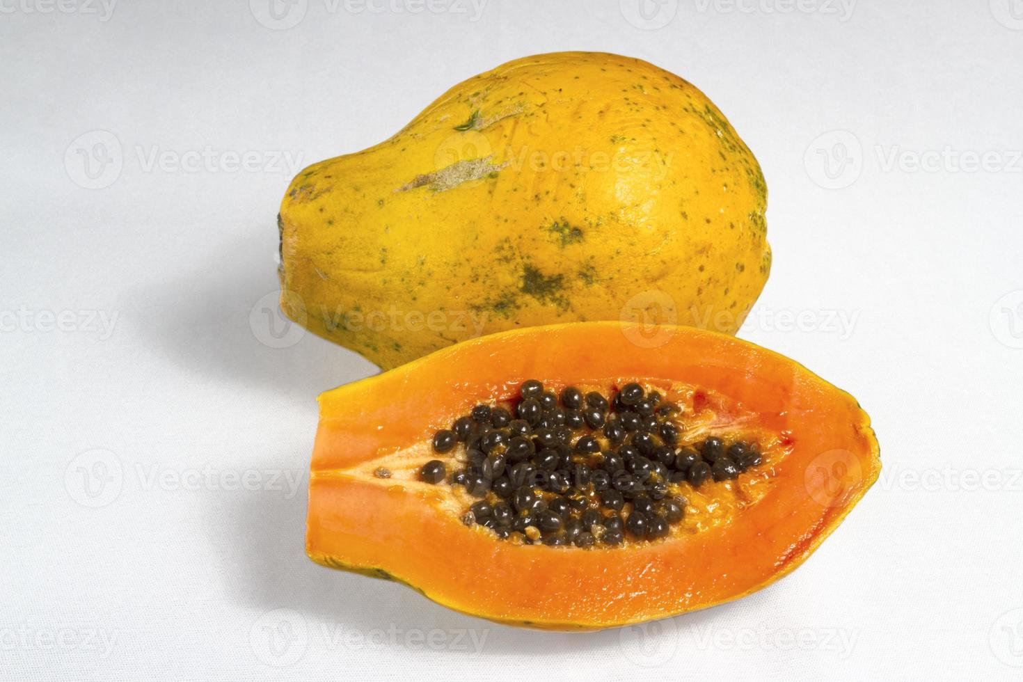 medio corte de papaya madura fresca con semillas aisladas en fondo blanco. enfoque selectivo. foto