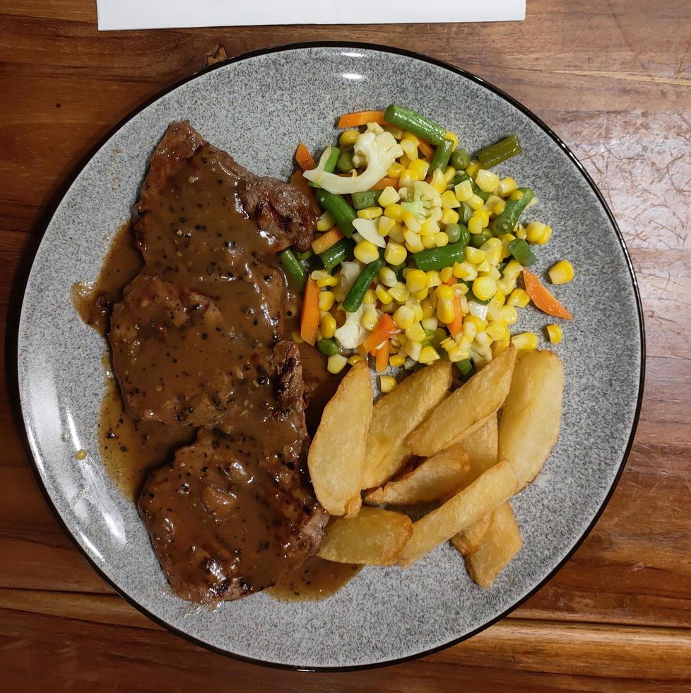 deliciosa y jugosa porción de filete a la parrilla servido con tomate y patata y otras verduras a la parrilla en un plato blanco foto