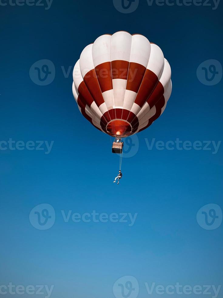 Man hanging from an air balloon photo