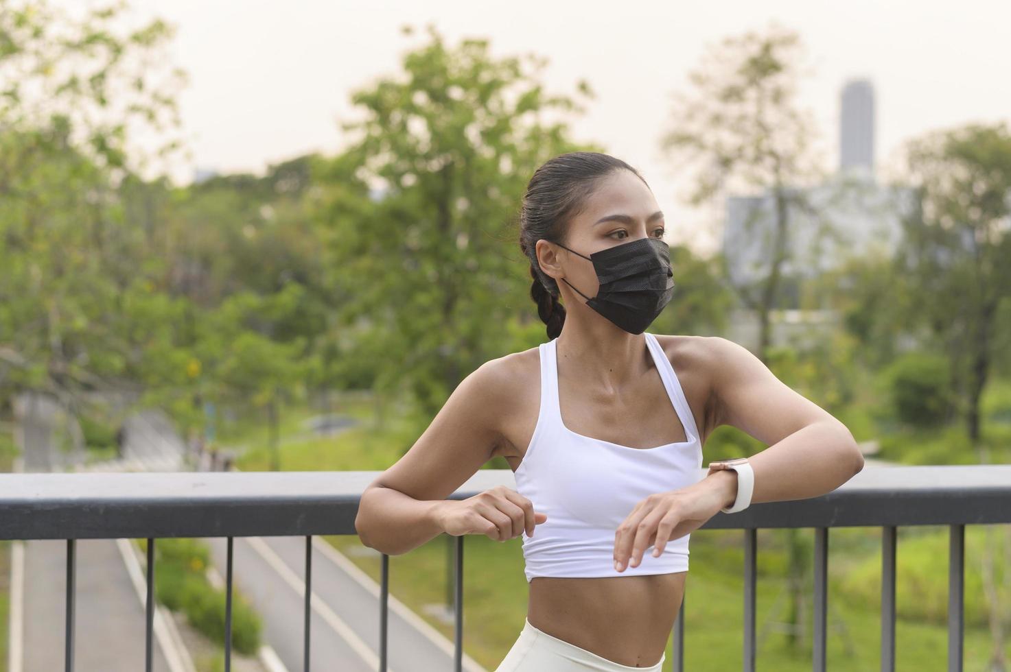 Young fitness woman in sportswear taking face mask in while exercise in city park, Health and Lifestyles. photo