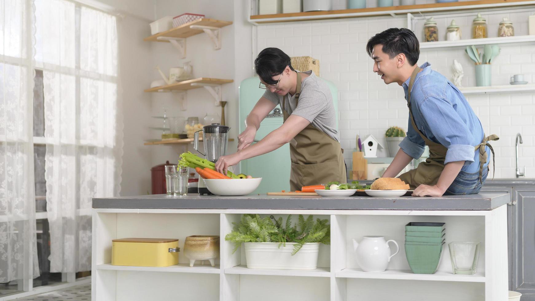 joven pareja gay sonriente cocinando juntos en la cocina en casa, lgbtq y concepto de diversidad. foto