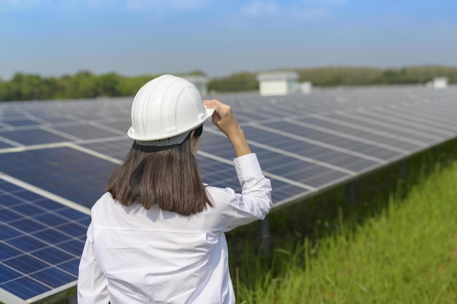 Female engineer wearing helmet in Photovoltaic Cell Farm or Solar Panels Field, eco friendly and clean energy. photo