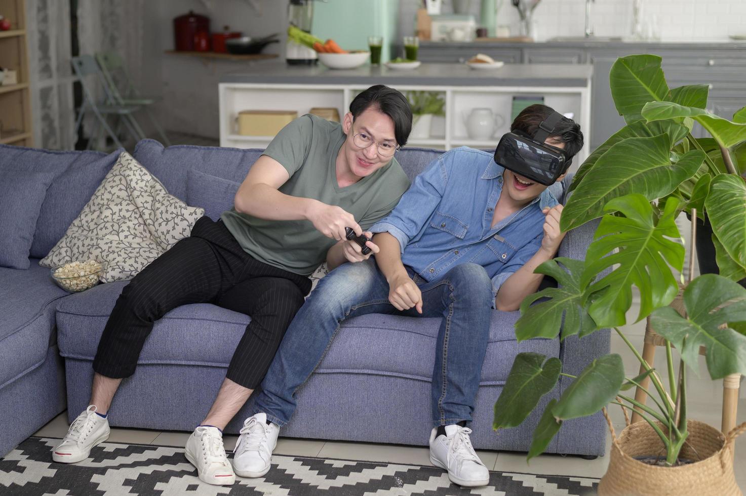 Young smiling gay couple playing video games in the living room at home, LGBTQ and diversity photo