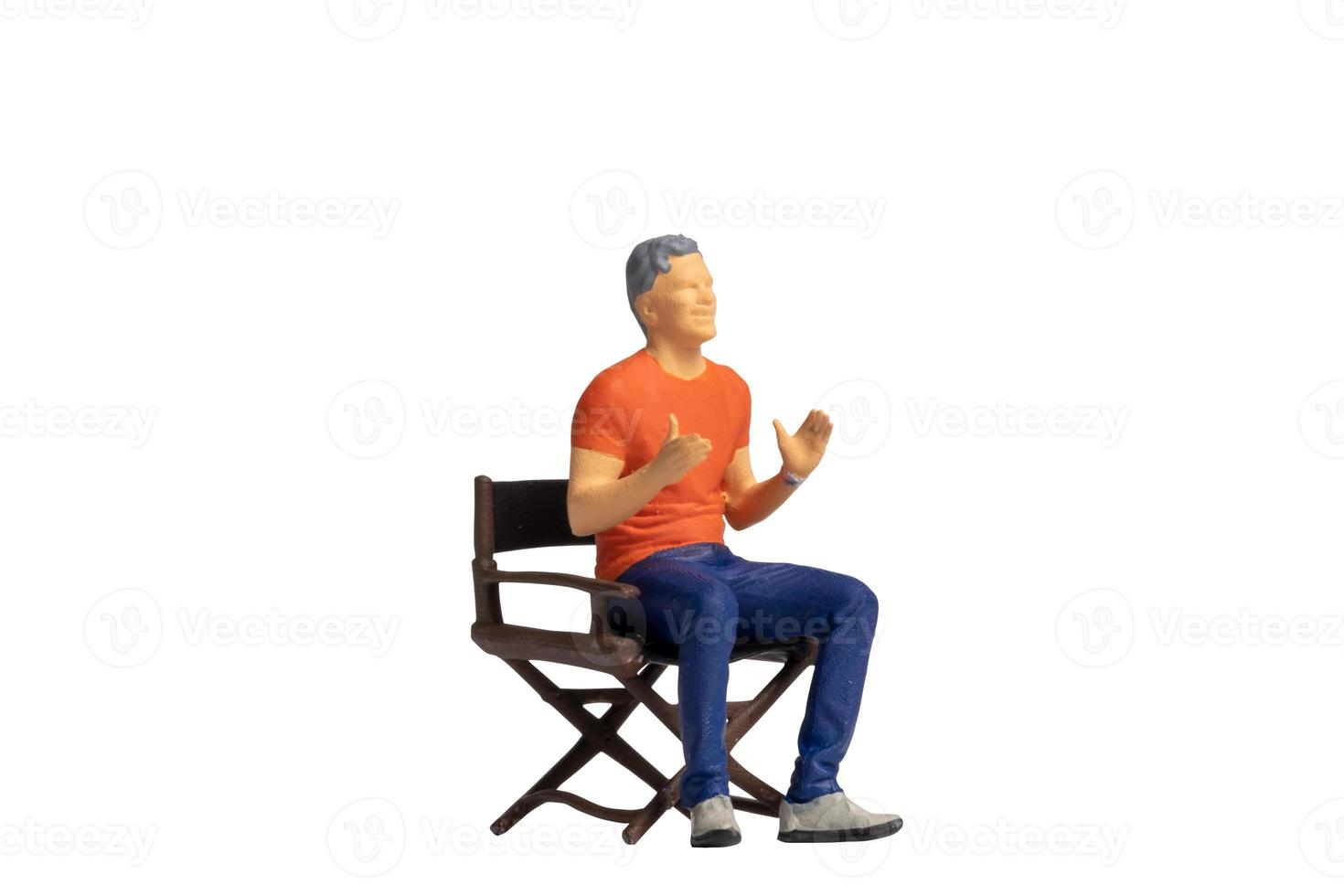 Miniature people sitting on chair isolated on white background photo