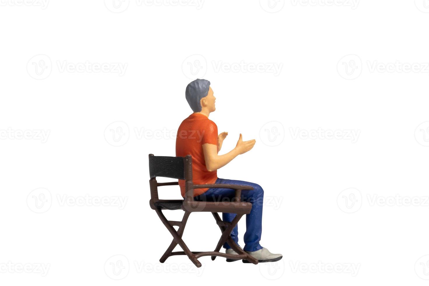 Miniature people sitting on chair isolated on white background photo