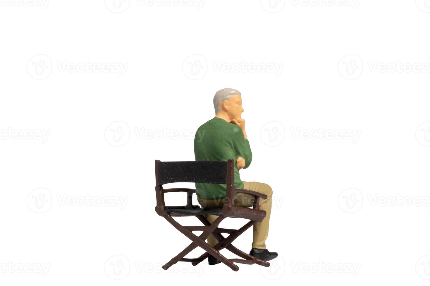 Miniature people sitting on chair isolated on white background photo