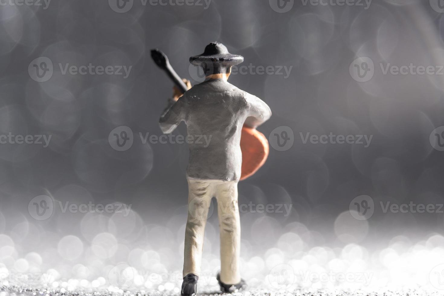 Miniature Musician with guitar on bokeh background photo