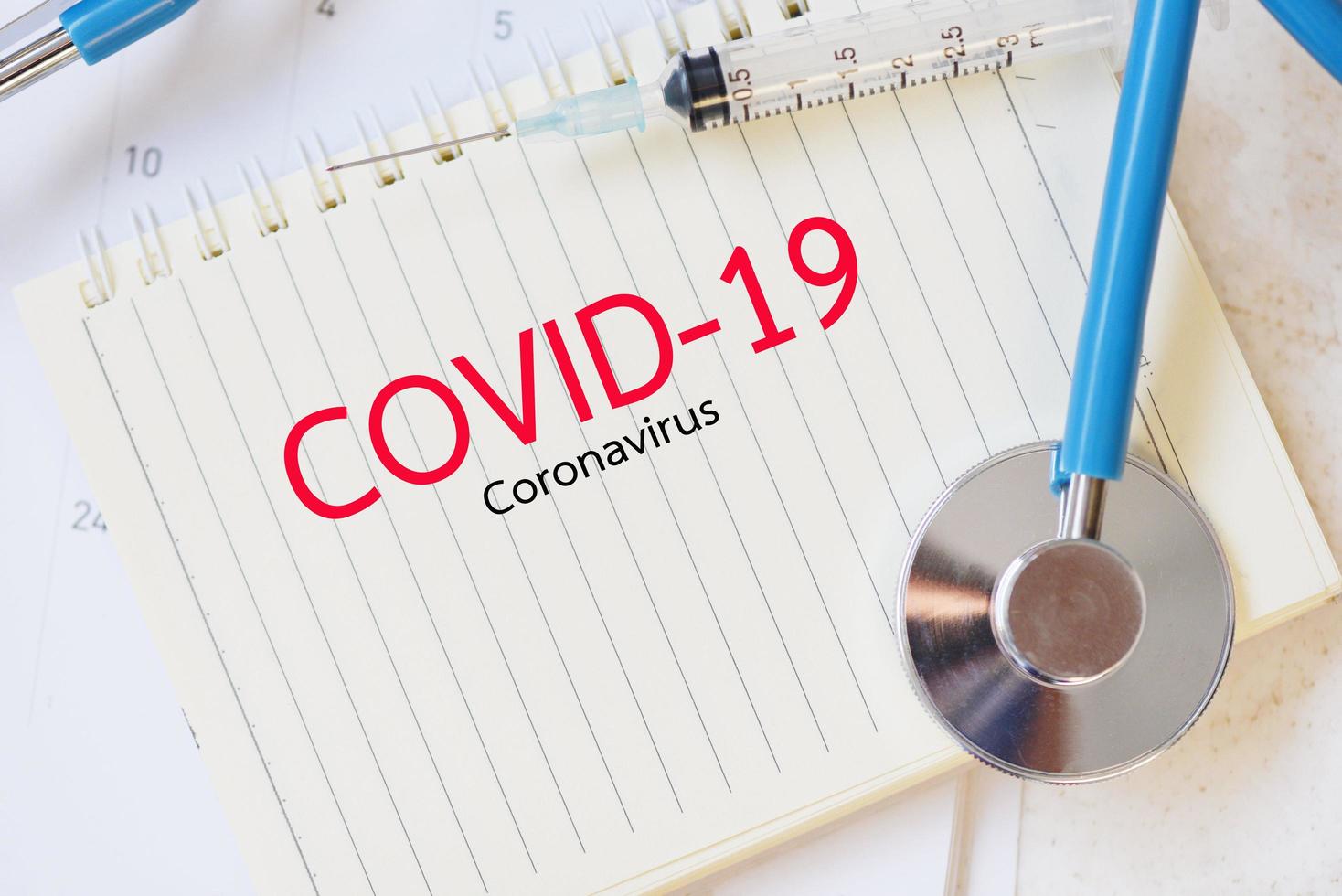 concepto de coronavirus covid-19 con medicamento de inyección de jeringa medicamento y estetoscopio en cuaderno de papel propagación de coronavirus influenza crisis médica pandemia prevención de riesgos de salud pública foto