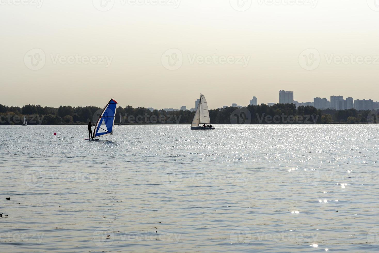 Windsurfer. Man is surfing on the background of skyscrapers. Man on a windsurf board. Windsurfing in the city. Water sports. Surfing with a sail. Windsurfing equipment. Active lifestyle. photo