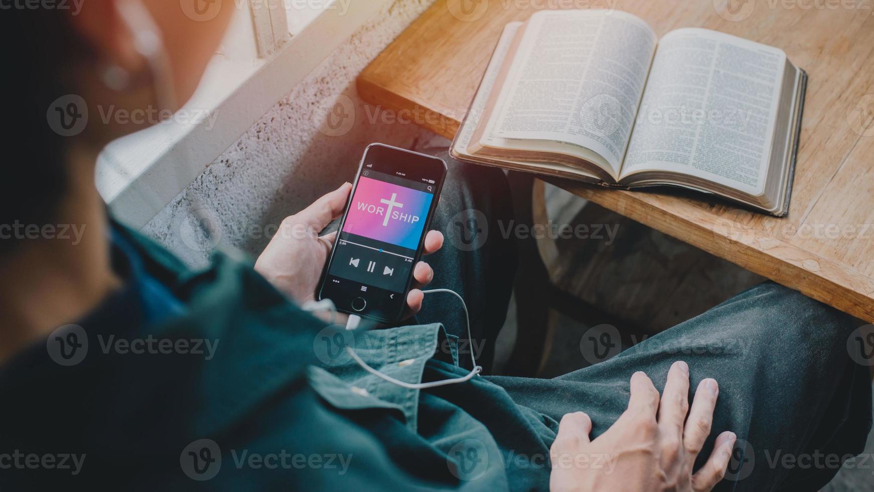 Man holding mobile phone praying worship to GOD with church online Sunday at home. Quarantine from Covid-19 Coronavirus pandemic. spirituality religion online concept photo