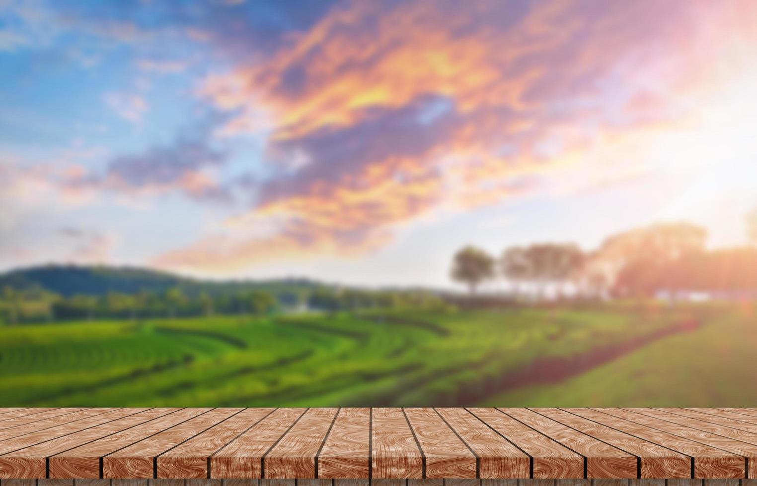 Wooden floor with beautiful sunset blur image of tea plantation background. photo