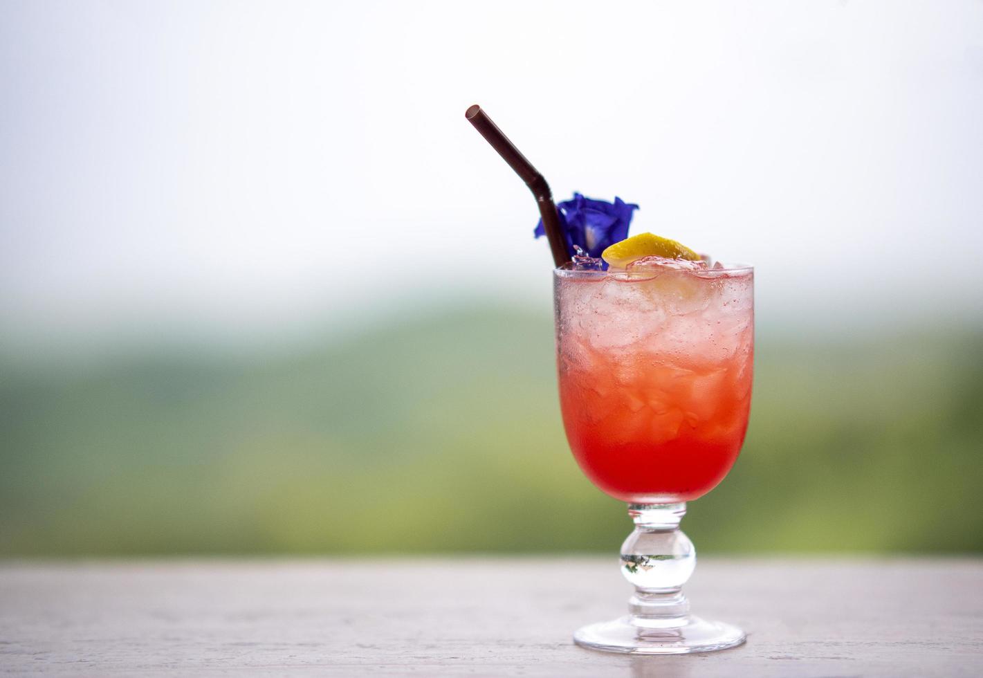 Italian red cold soda on wooden table in natural atmosphere against blurred background. photo