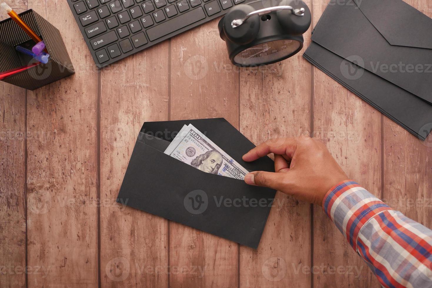 person hand putting cash in a envelope. top view photo
