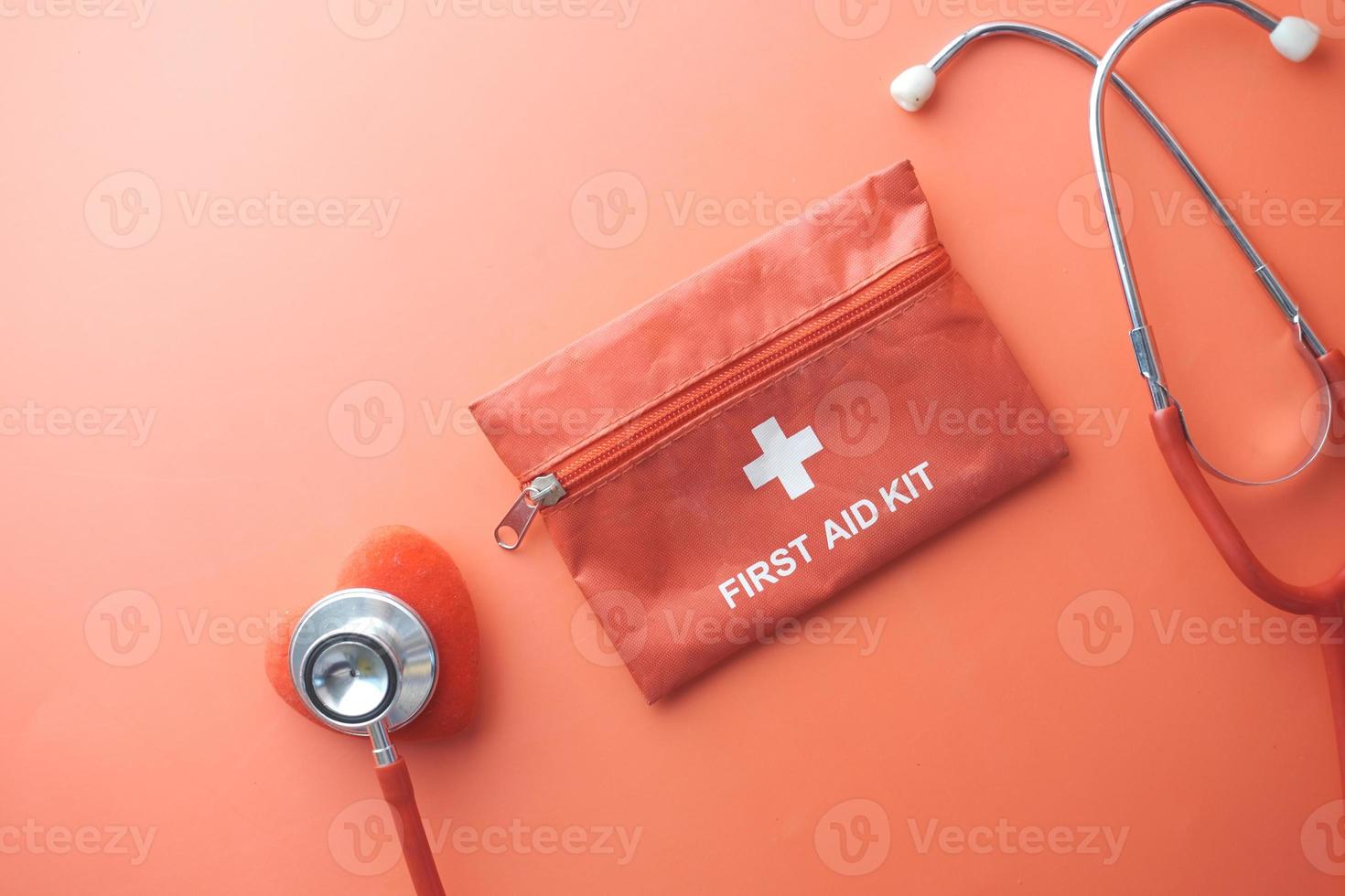 top view of first aid kit, heart shape symbol and stethoscope on red photo