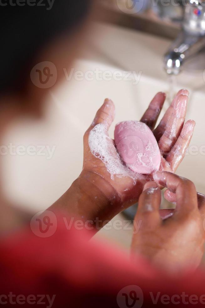 young man washing hands with soap warm water photo