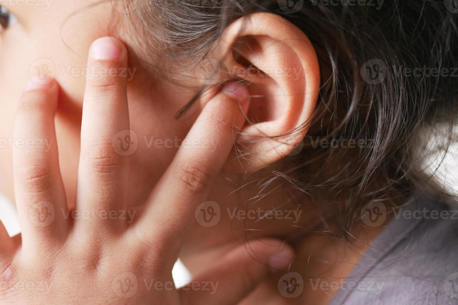 child girl having ear pain touching his painful ear , photo