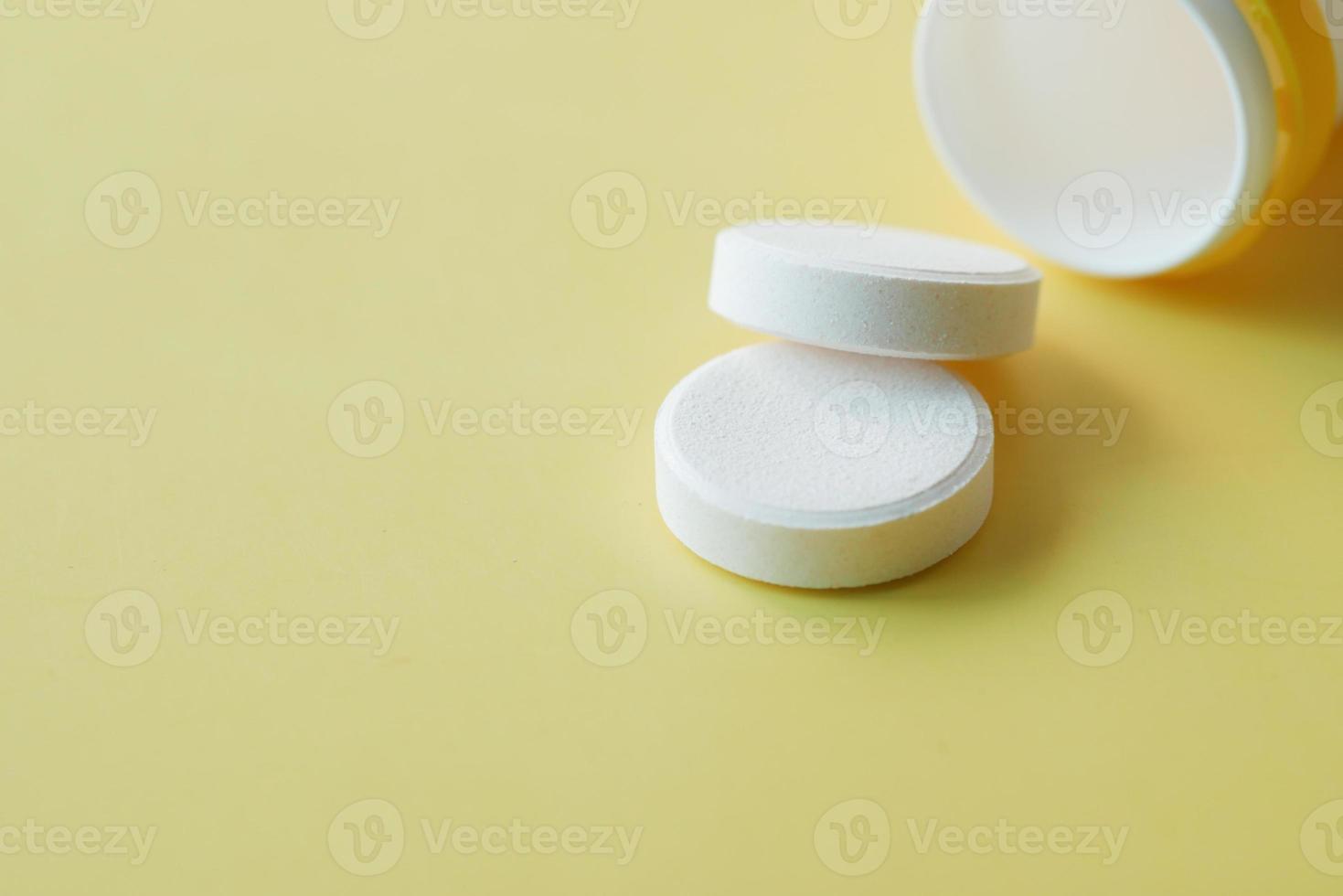 Effervescent soluble tablet pills on yellow background photo