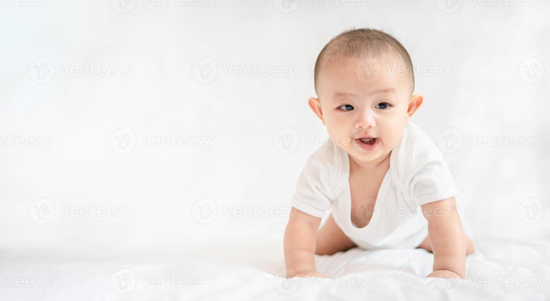 familia feliz, lindo bebé asiático recién nacido acostado jugar en la cama blanca mira la cámara con una sonrisa sonriente cara feliz. pequeño inocente nuevo bebé adorable niño en el primer día de vida. concepto del día de la madre. foto