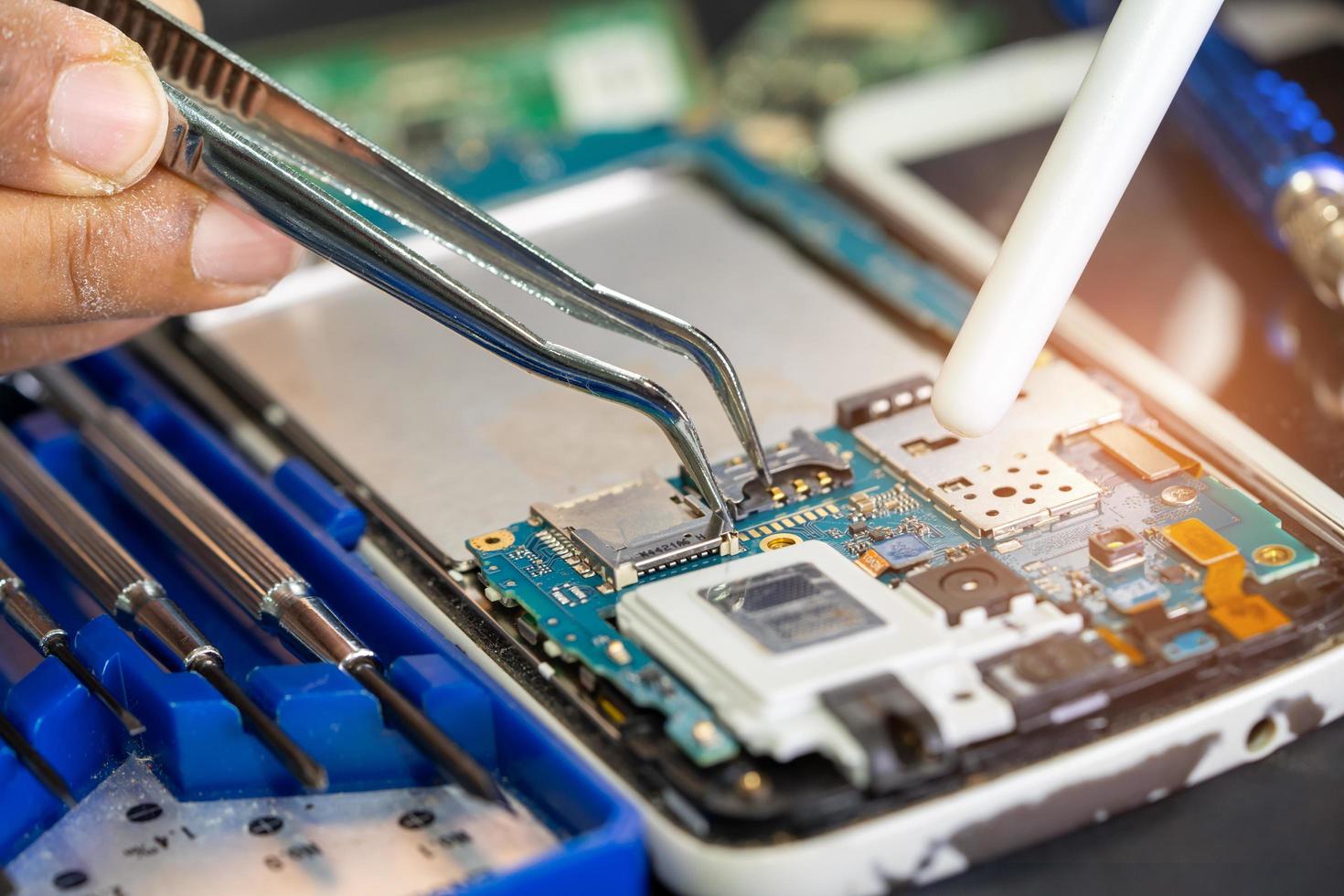 Technician repairing inside of printed circuit board PCB by soldering iron. Integrated Circuit. the concept of data, hardware, technician and technology. photo