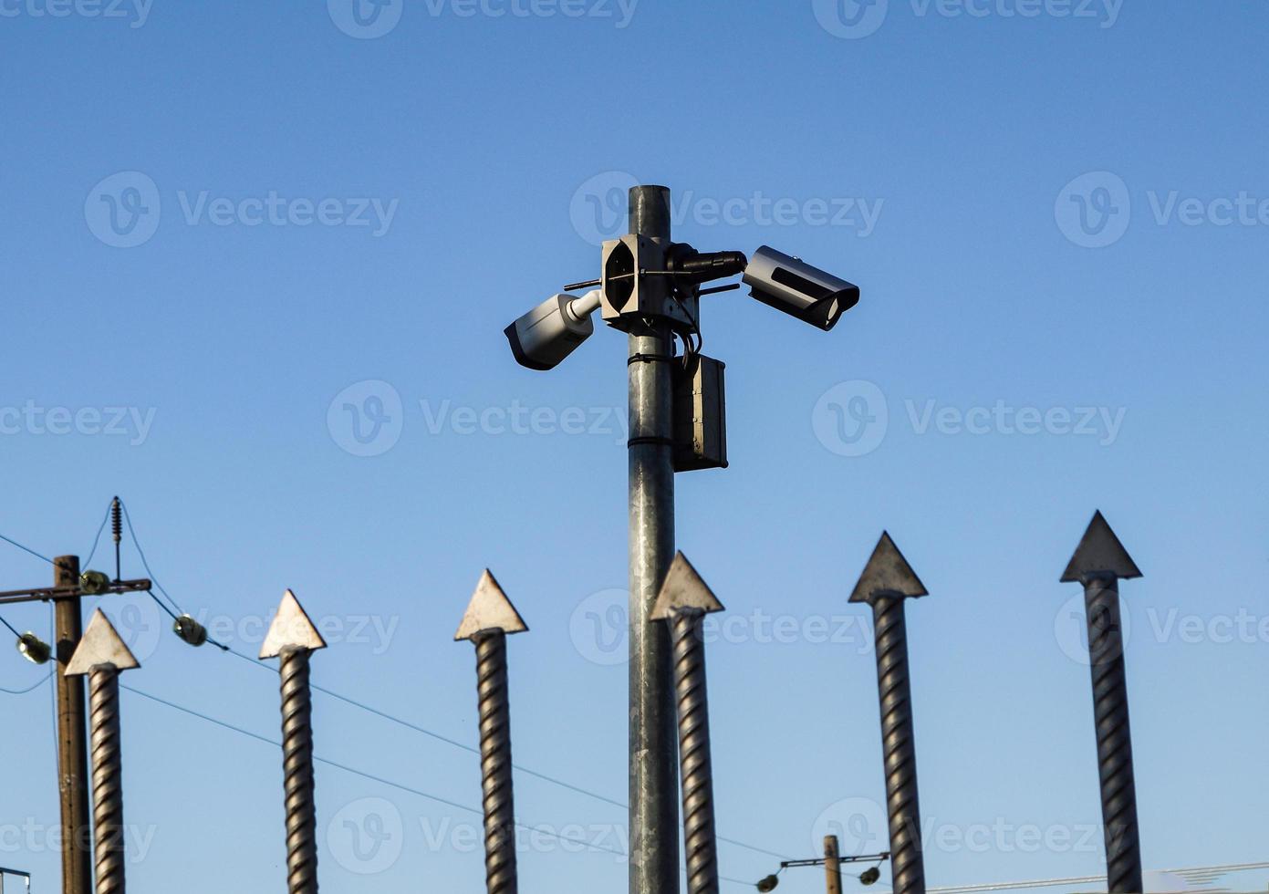 Video cameras over iron fence spikes on blue sky photo