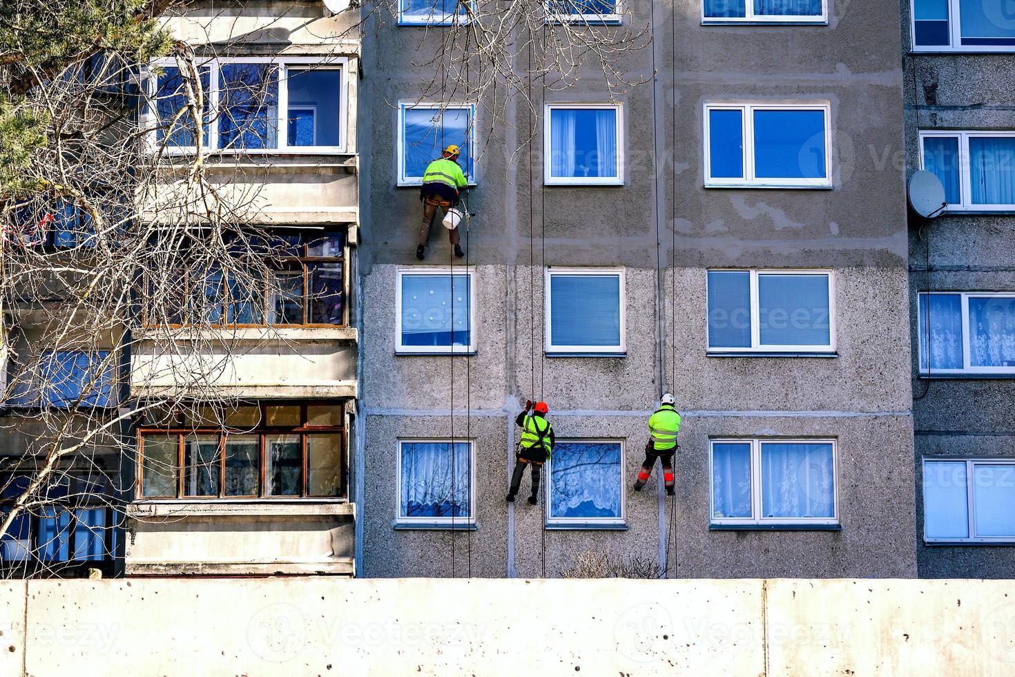 Window cleaning urban alpinism brigade on building with windows and balconies on spring cleaning day photo