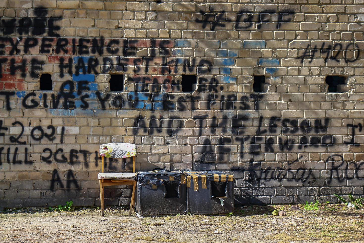 Black paint writings on yellow brick wall with chair standing near and long shadows photo