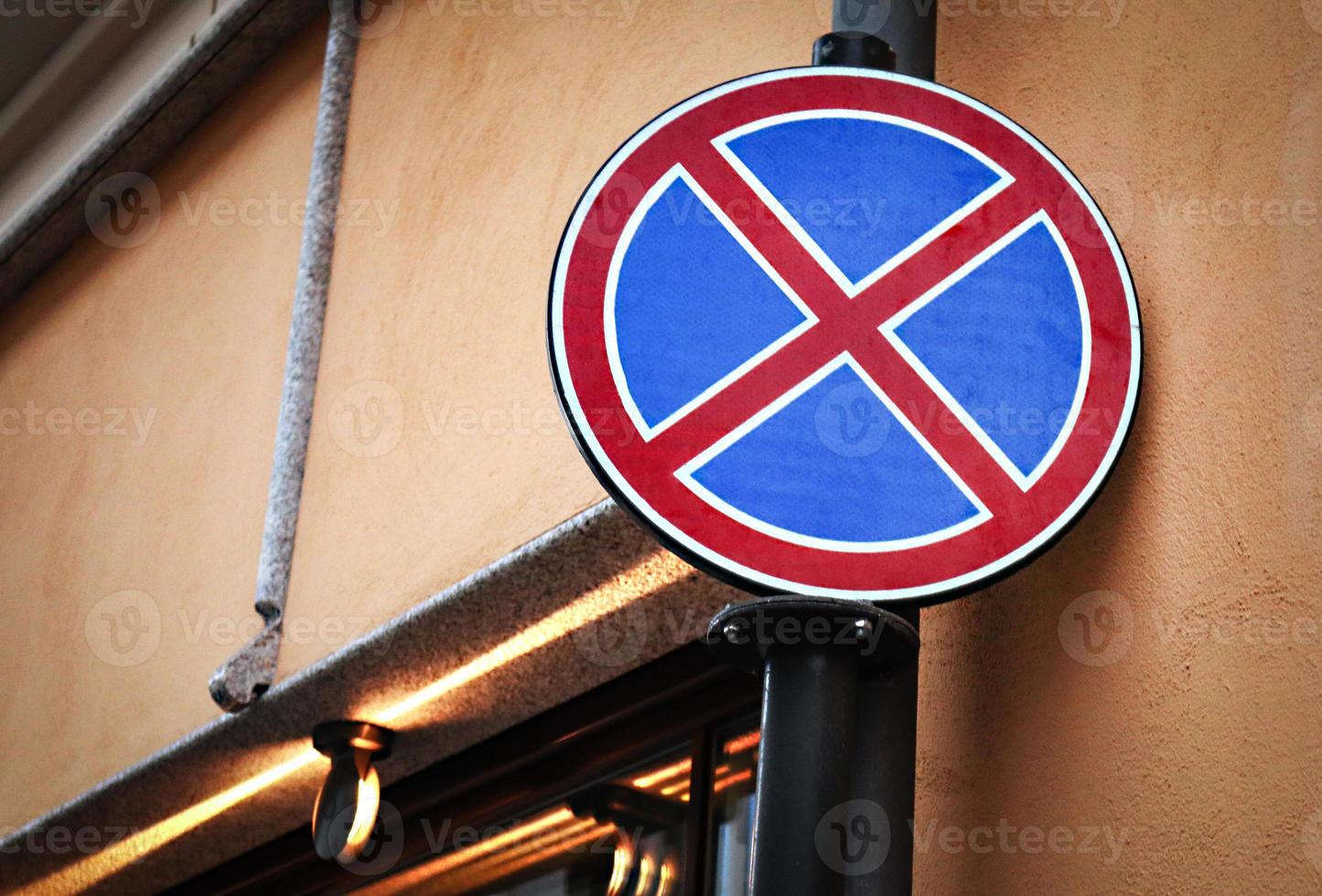 No stopping round road sign hanging on brown concrete wall building corner photo