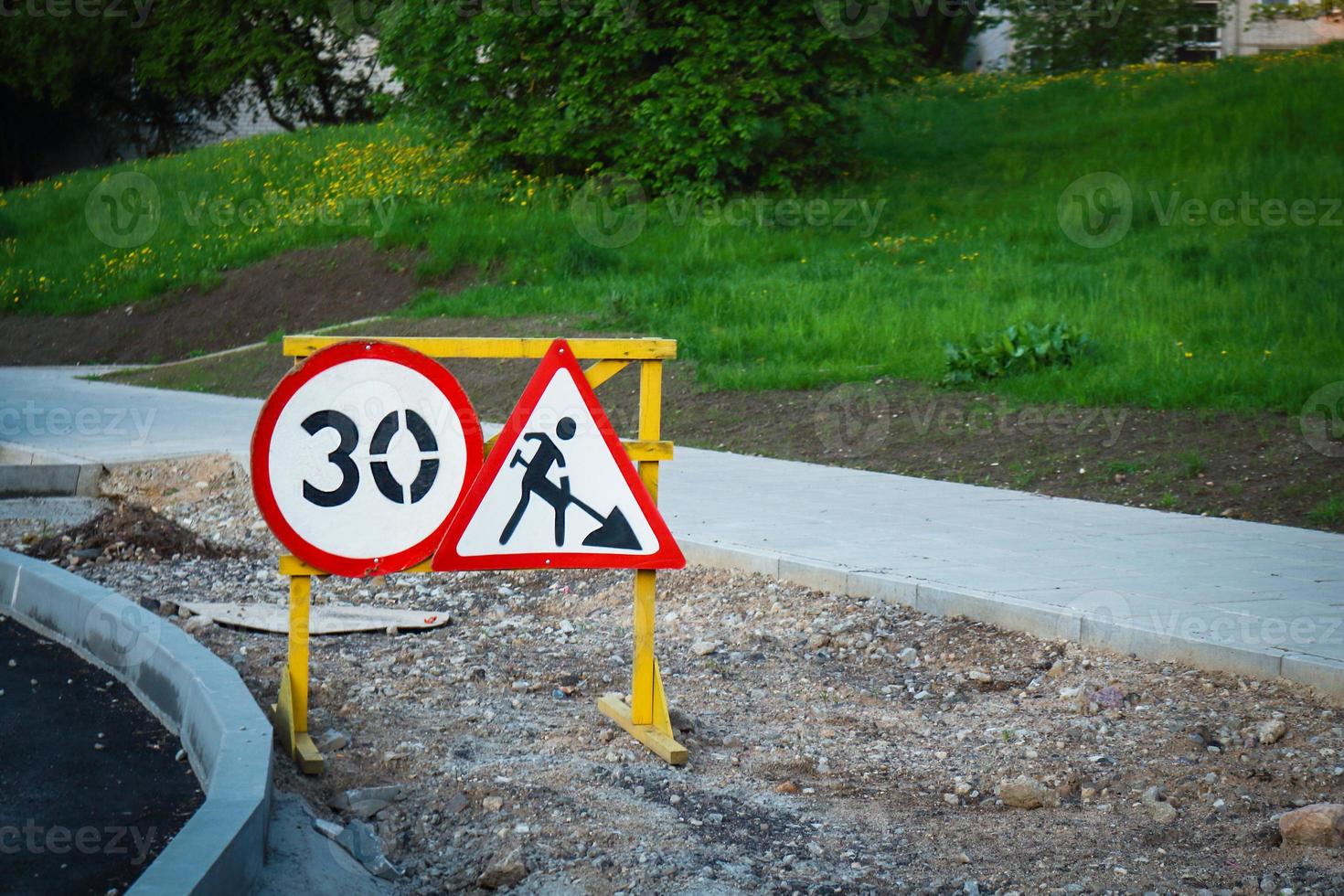 Construction road signs with number and digging man with shovel symbol on sandy road under construction photo