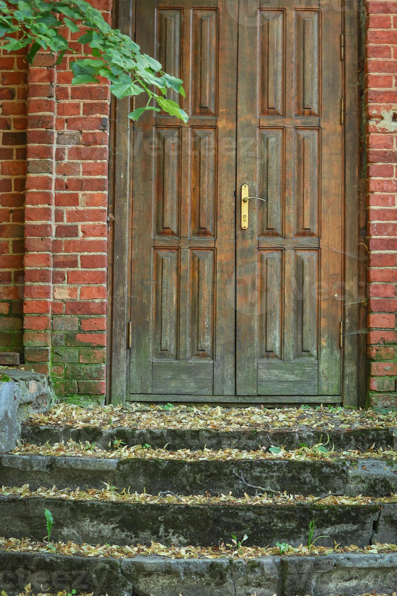 Old brown wooden door in red brick wall building with weathered green  stairs 7236244 Stock Photo at Vecteezy