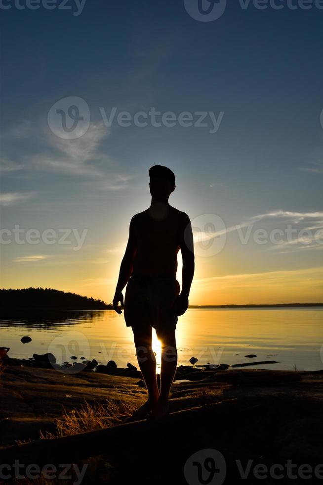 Man's silhouette shadow in sunset near the lake photo