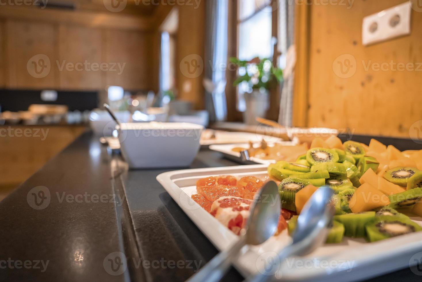 Various healthy sliced fruits served in plate on counter at luxurious hotel photo