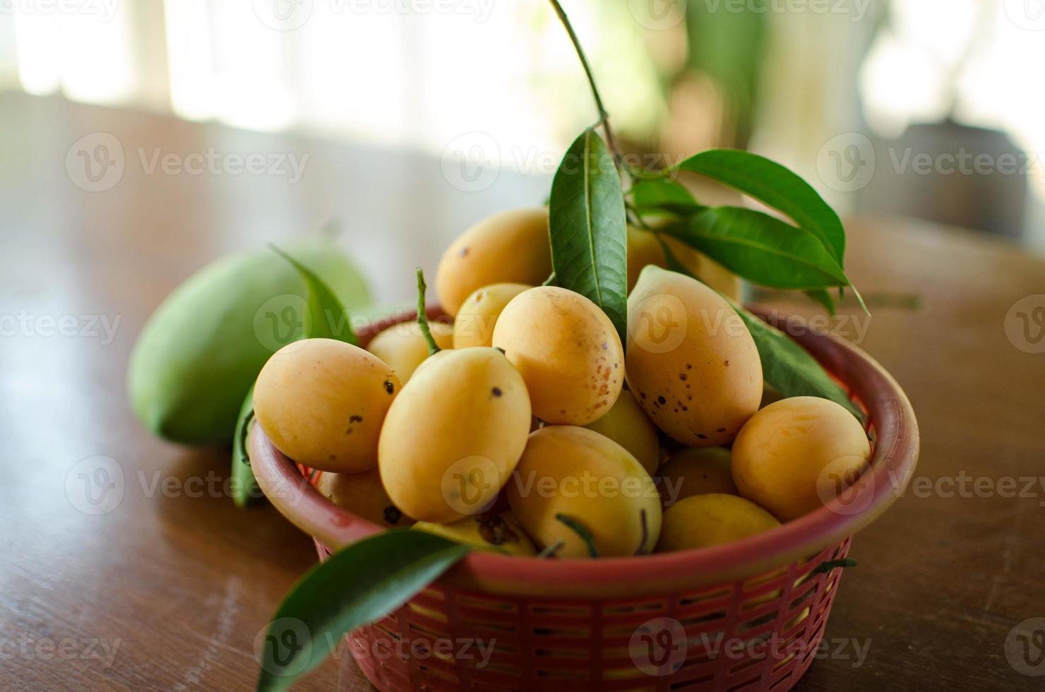 Marian Plum in a basket - Thailand agriculture, Asian tropical fruits display on the table with blur background and selective focus. Copy space. photo