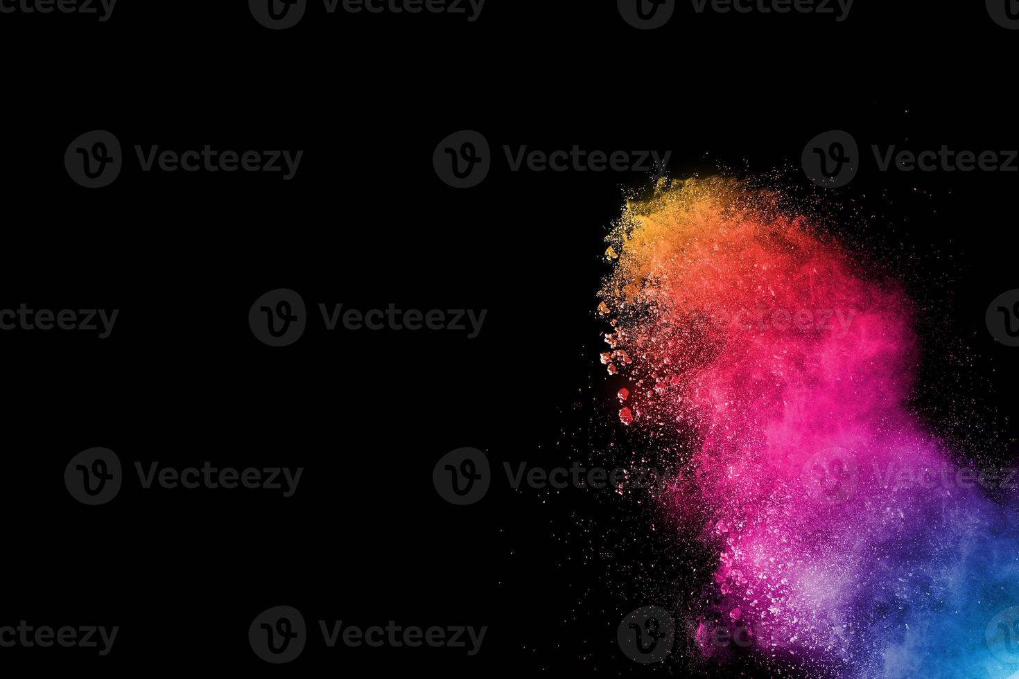 explosión de polvo multicolor sobre fondo negro. salpicaduras de polvo azul rosa y naranja. foto