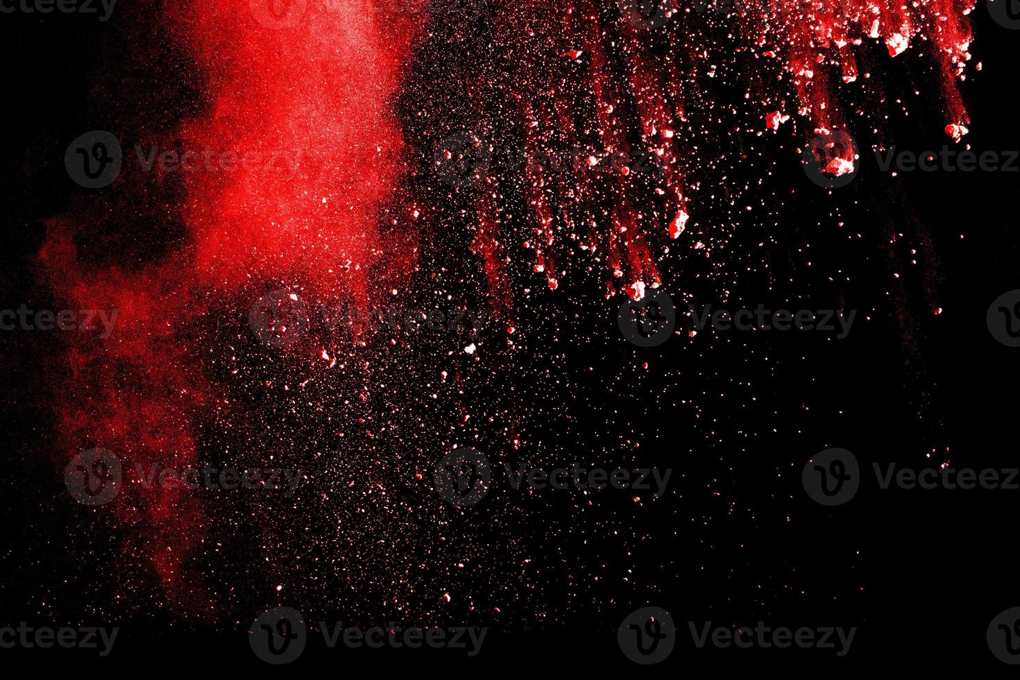 Red powder explosion cloud on black background. Freeze motion of red color dust  particle splashing. photo