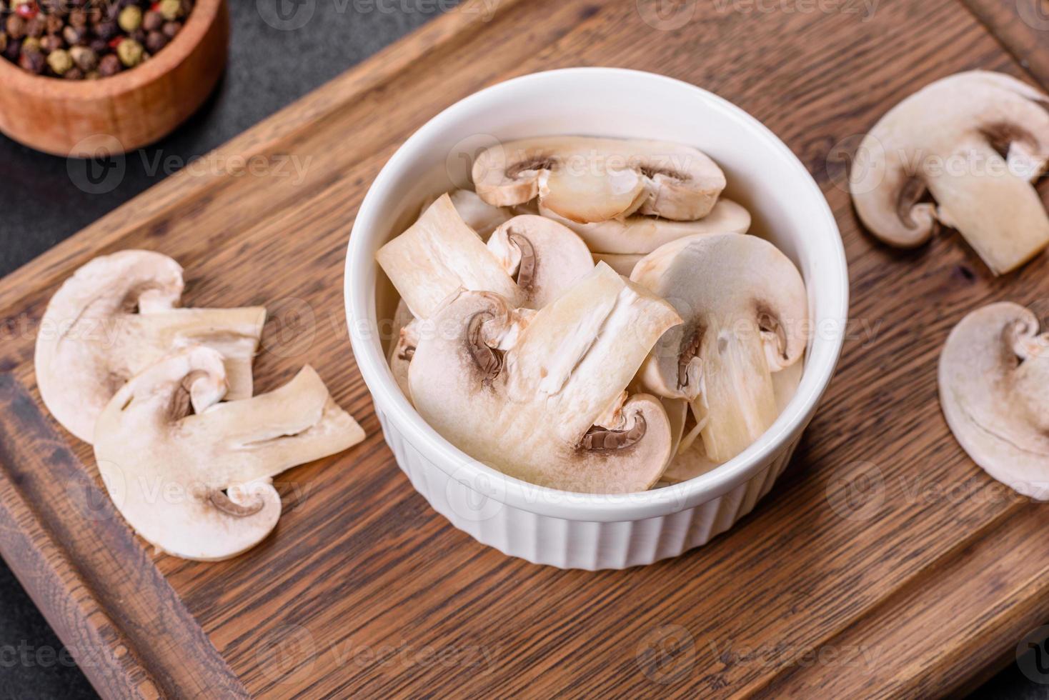 Beautiful young white champignons torn to slices on a dark concrete background photo