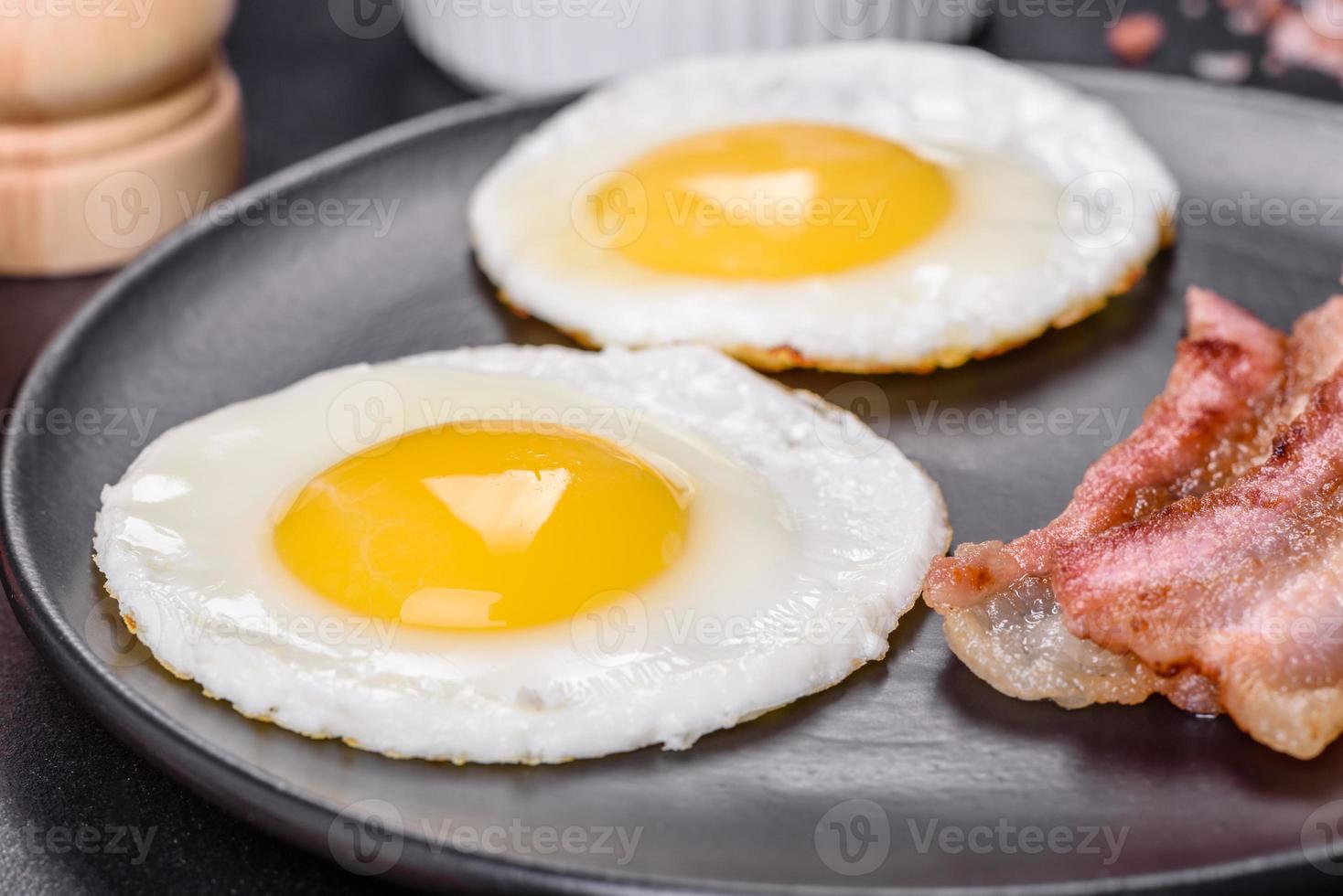 English breakfast with fried eggs, bacon, beans, tomatoes, spices and herbs photo