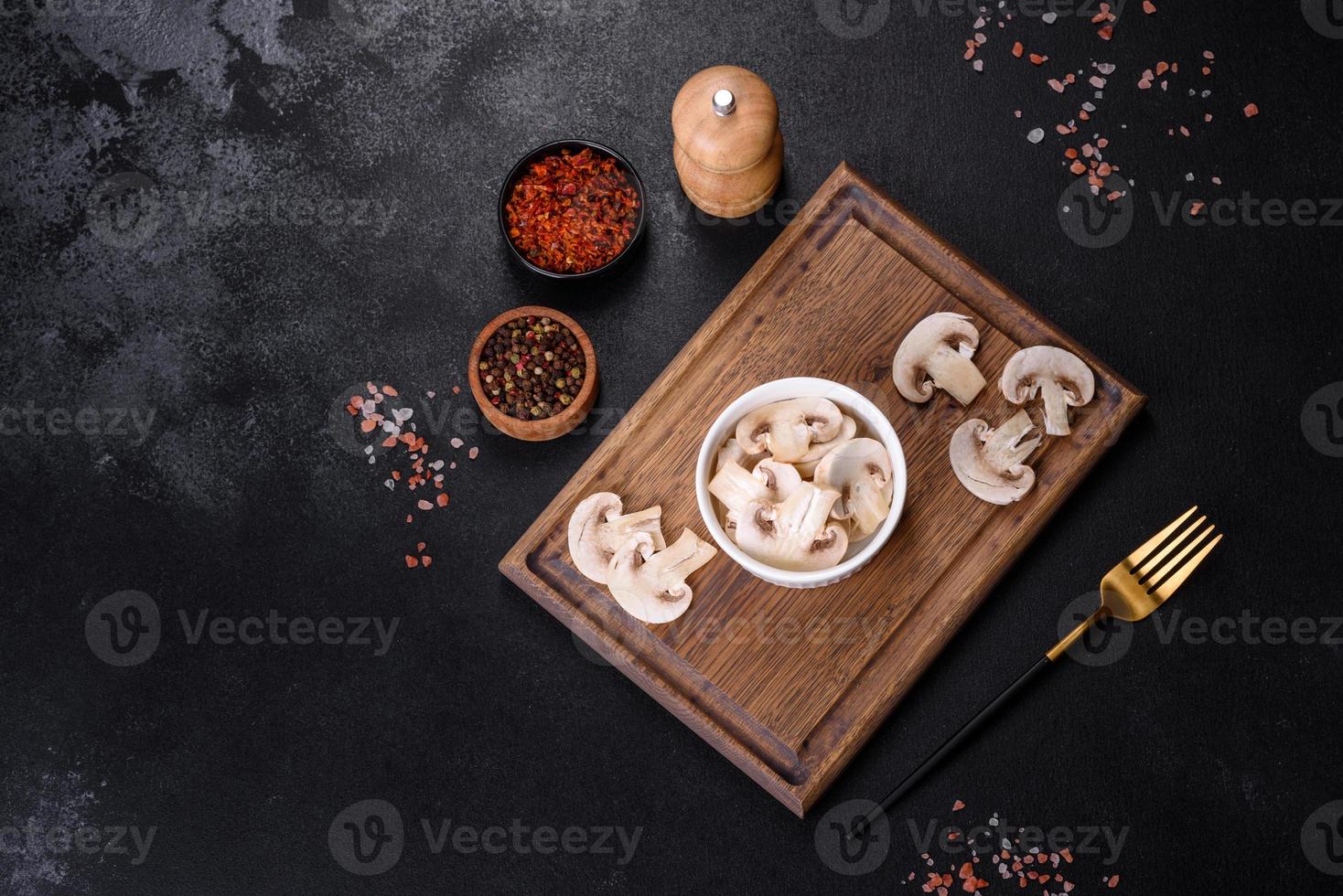Beautiful young white champignons torn to slices on a dark concrete background photo
