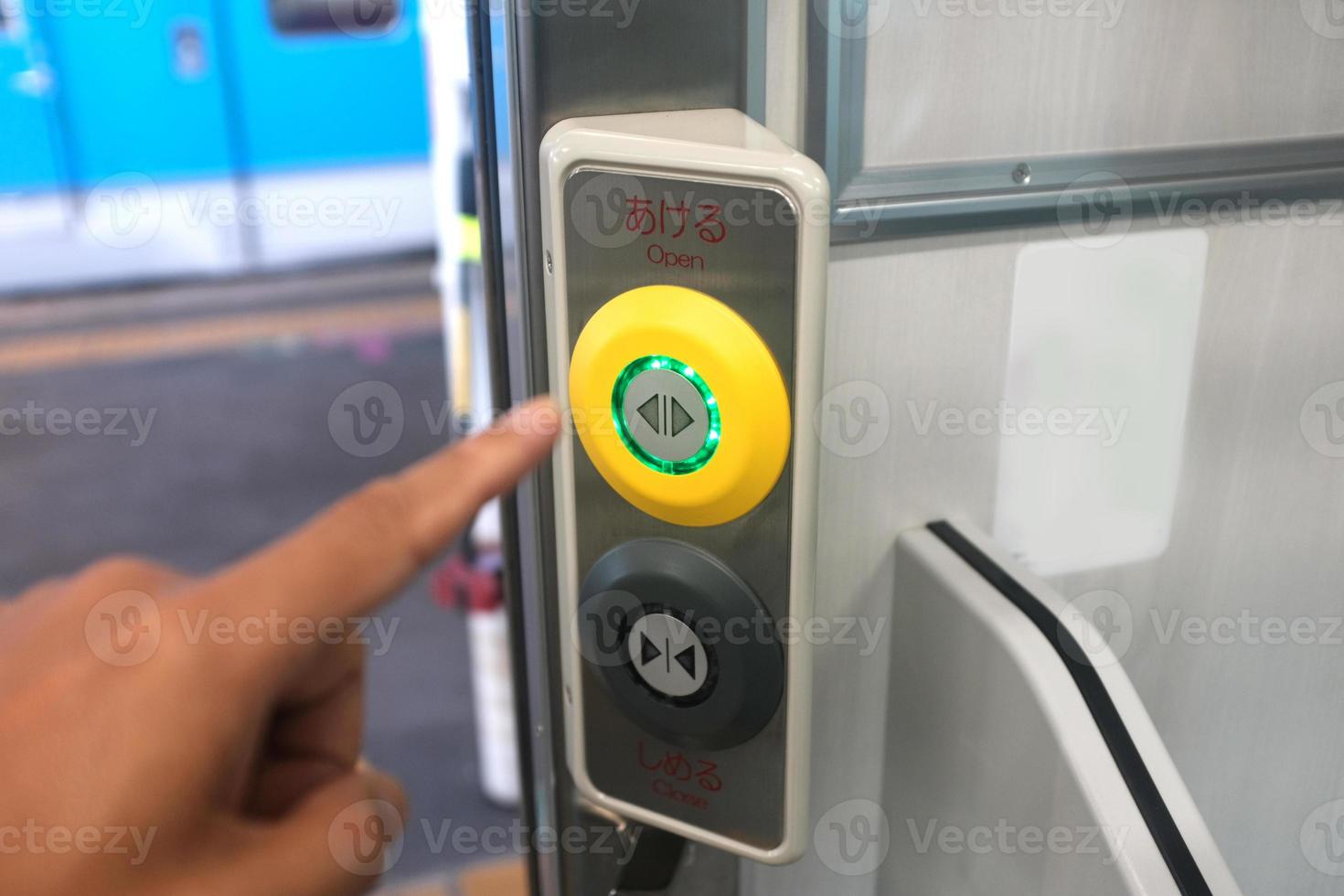 Close up of a hand pressing the close button on the side of the train door entrance photo