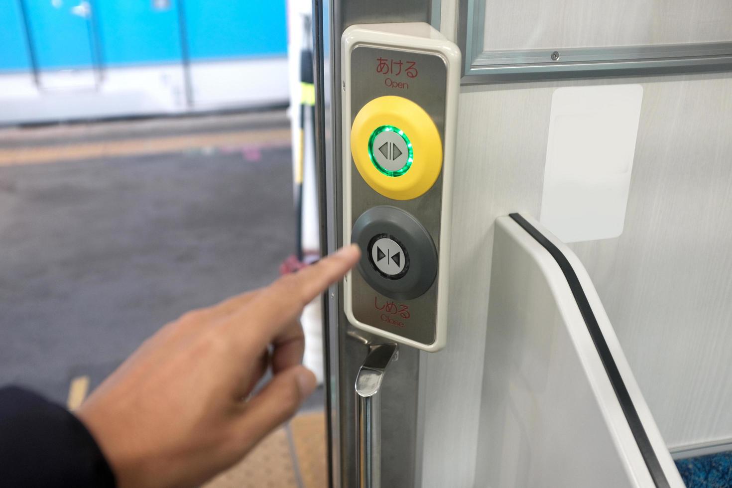 primer plano de una mano presionando el botón de cierre en el costado de la entrada de la puerta del tren foto