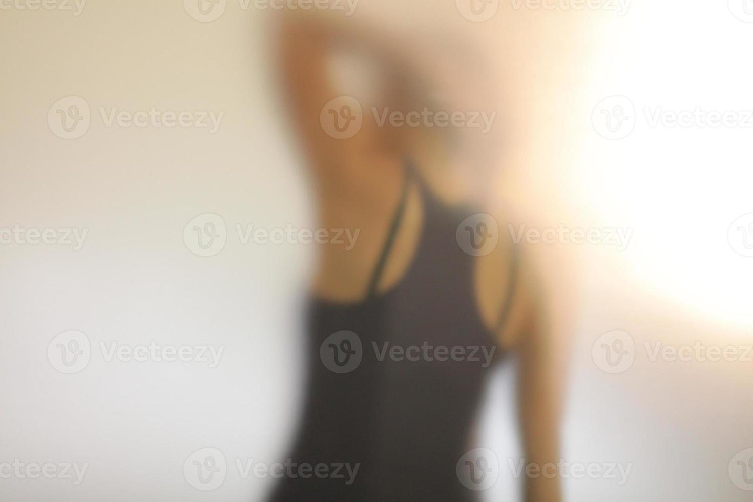 View of a woman about to take off her clothes behind a blurry frosted glass photo