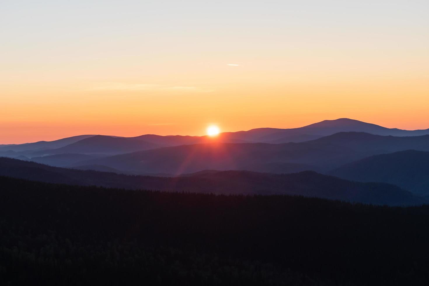 Beautiful and bright sunrise in the mountains. The sun's rays make their way from the tops of the misty mountains photo