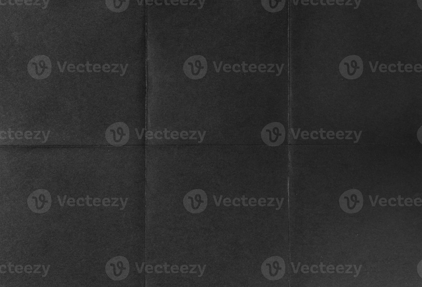 Black crumpled unfolded paper sheet texture background. Paper folded in six. Full frame photo