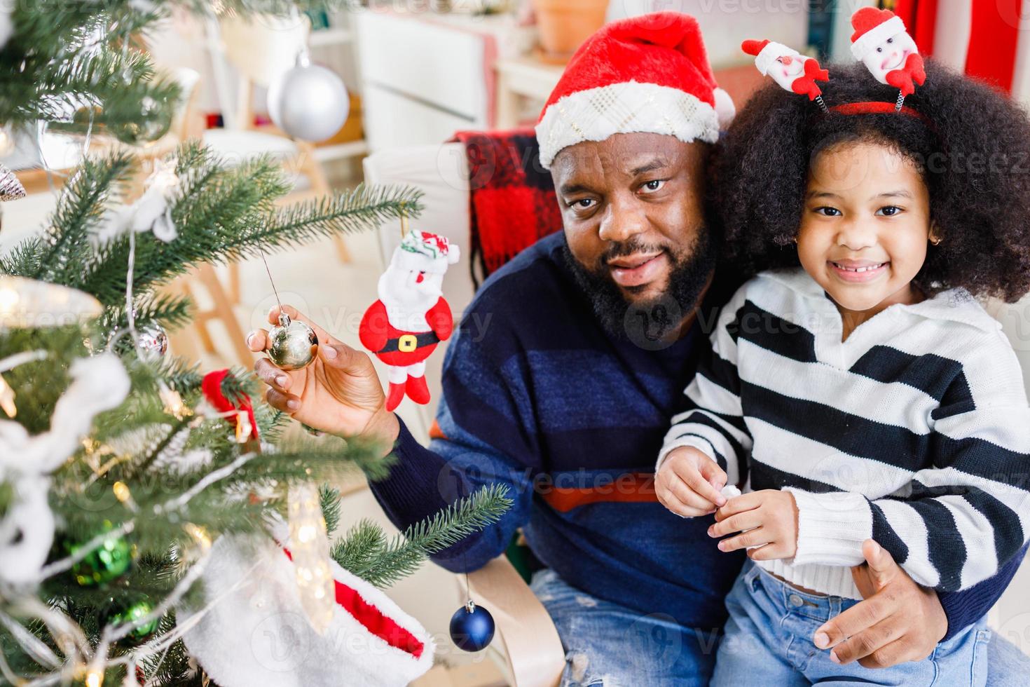 African American family help decorate the Christmas tree at home. Merry Christmas. photo