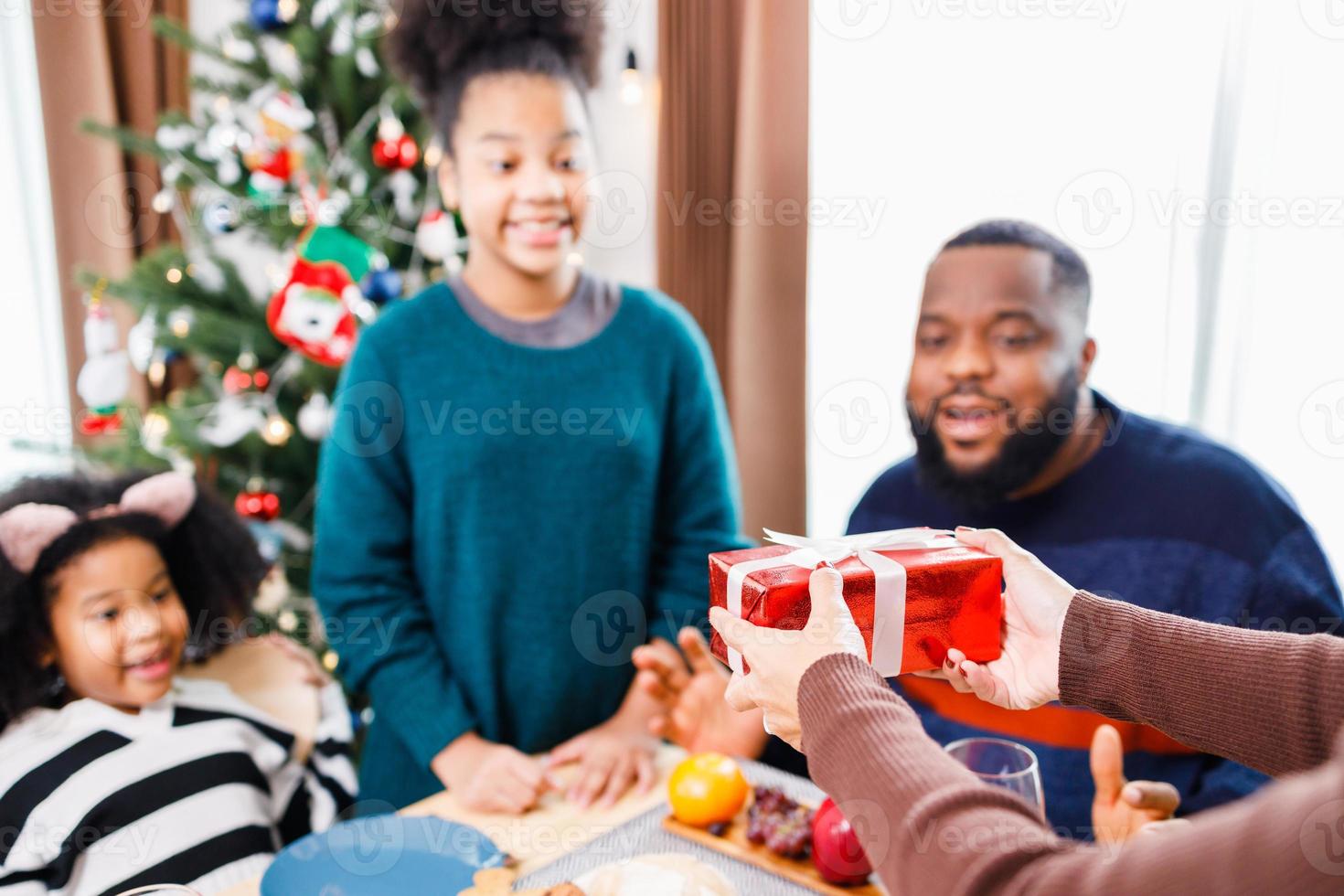 African American family surprising together with a gift on Christmas day while dinner. photo