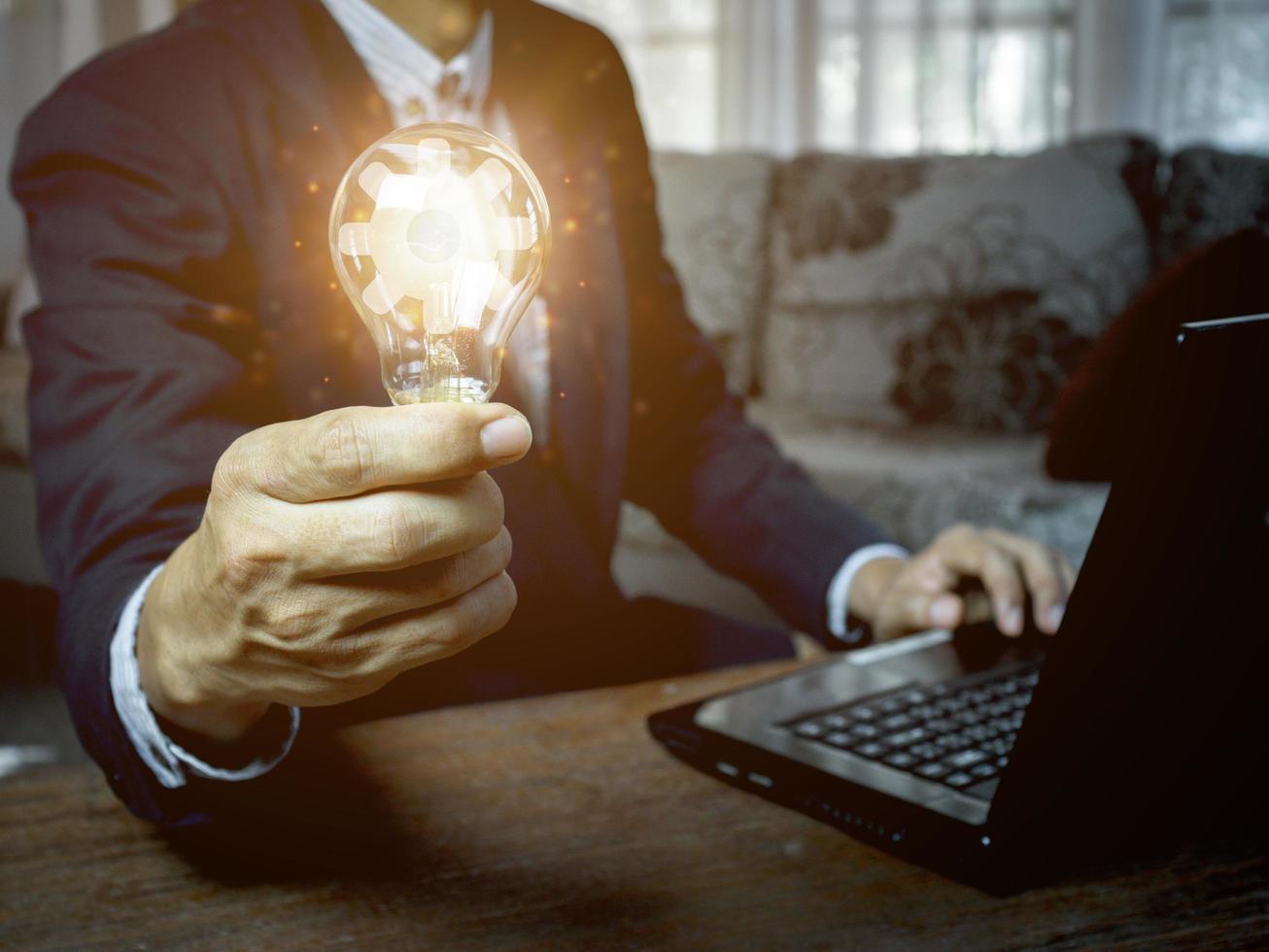 hand of a man with a light bulb And there is a gear icon in it photo