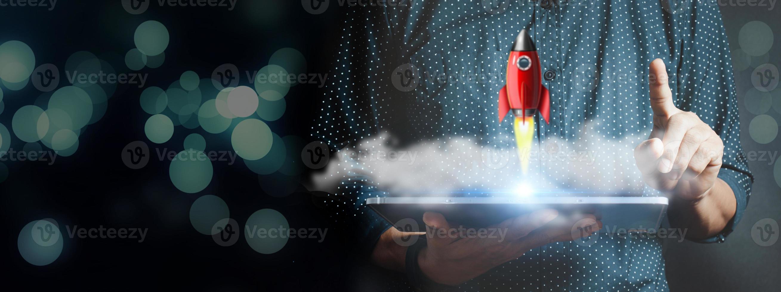 Businessman holding tablet and icon transparent rocket photo