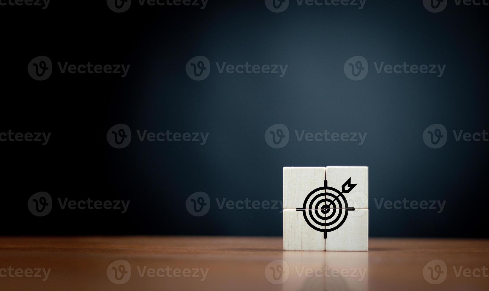 Focus on a goal and achieve successful business. Initiation for planning to reach target. Darts target aim icon on wooden cubes with dark  background. Copy space. photo