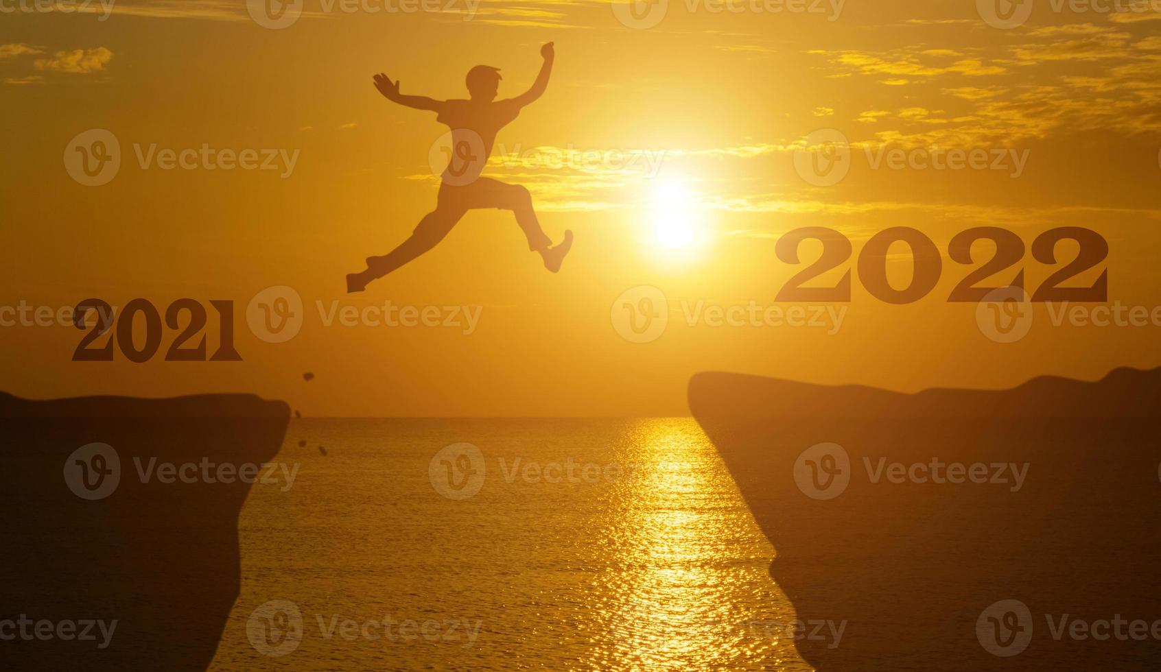 Silhouette man jump between 2021 and 2022 years with sunset background. photo