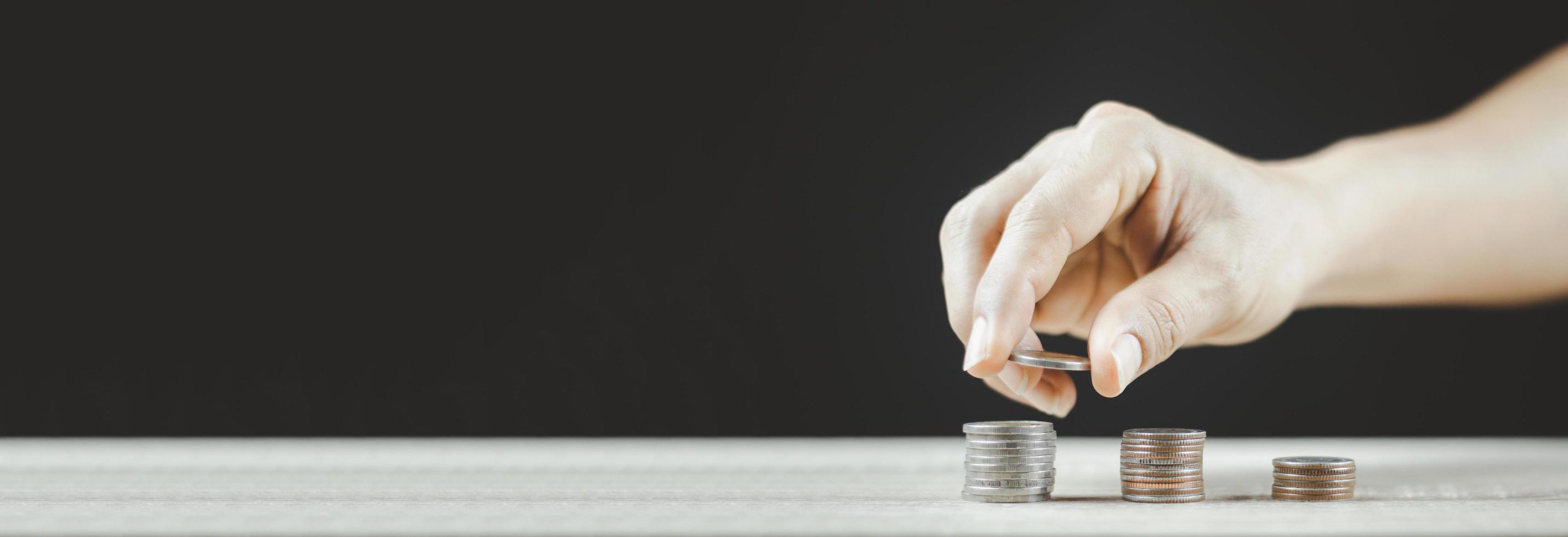 mano masculina poniendo dinero pila de monedas para el futuro negocio en crecimiento. foto